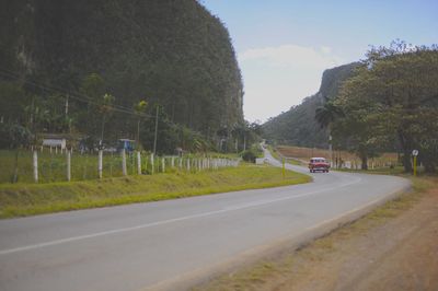 Road by trees against sky