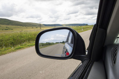 Car mirror and highway view, black car