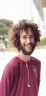 Portrait of smiling man listening music in city