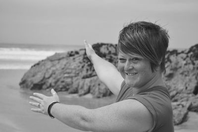 Portrait of smiling young woman gesturing while standing at beach