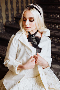 Beautiful teenage girl wearing wedding dress while sitting on steps