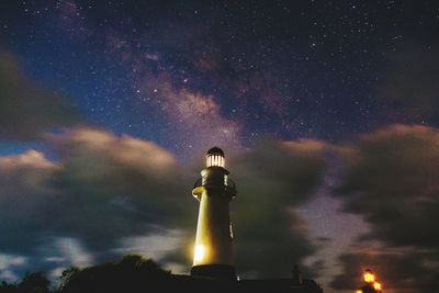 Low angle view of illuminated lighthouse against sky at night