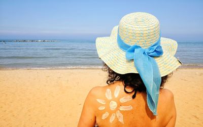 Rear view of woman with suntan lotion on back at beach