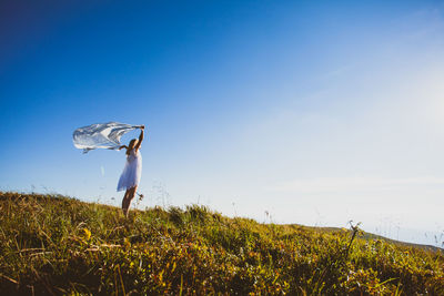 Woman with arms raised on field against sky