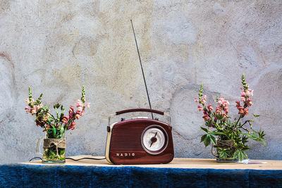 Flower vases and a retro radio on a table against concrete wall