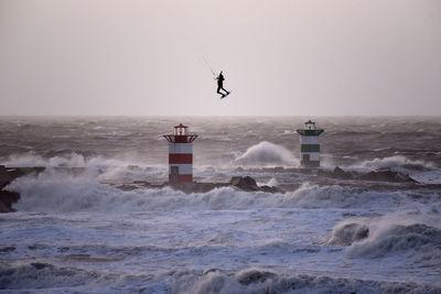 Person kiteboarding on sea against clear sky