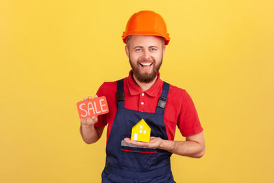 Portrait of young man standing against yellow background