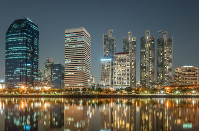 Illuminated buildings by city against sky at night