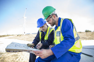 Engineers at wind farm looking at map