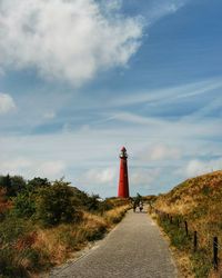 Lighthouse amidst road and buildings against sky