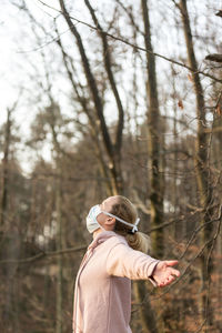 Woman standing by tree in forest