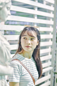 Young woman looking away by sculpture against window