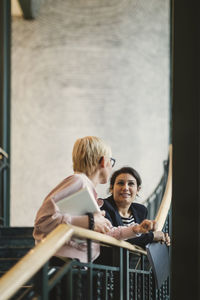 Portrait of young couple standing against railing