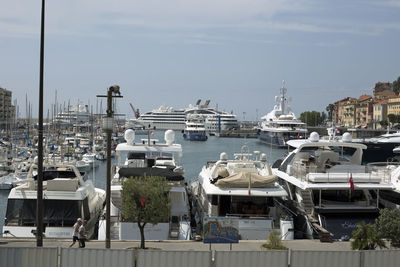 Boats moored at harbor against sky in city