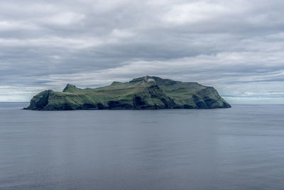 Idyllic shot of island in sea against cloudy sky