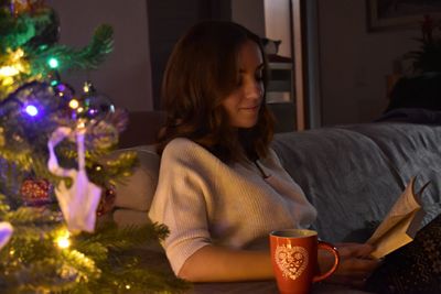 Woman looking at illuminated christmas tree at home