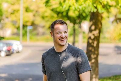 Portrait of smiling young man standing against trees