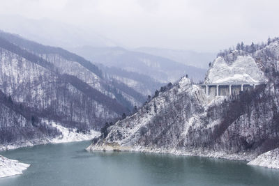 Scenic view of mountains by lake against sky during winter