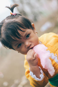 Close-up portrait of cute girl eating cotton candy