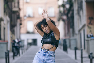 Woman dancing on street against building