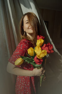 Close-up of woman holding red rose in bouquet