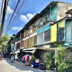 People on street by buildings in city against sky