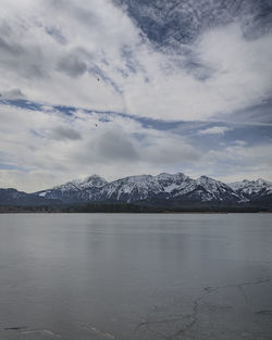 Scenic view of lake by snowcapped mountains against sky