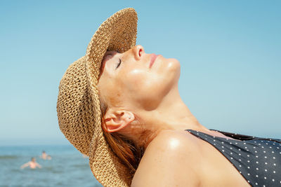 Close-up of woman in hat relaxing at beach