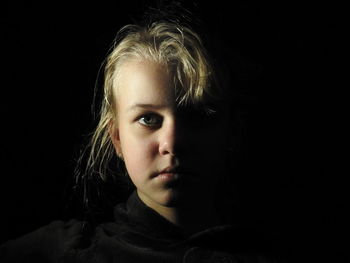 Close-up portrait of teenage girl against black background