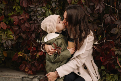 Happy mother and little son child walking in the autumn forest in nature in fall