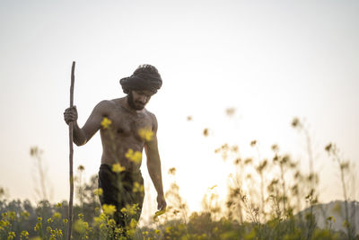 Young indian farmer with a stick walking in a wasteland. crops not growing due to shortage
