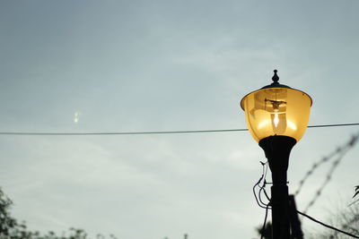 Low angle view of illuminated street light against sky