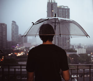 Rear view of man standing in city against sky