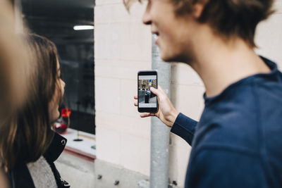 Teenage boy showing mobile phone to friend while standing in city