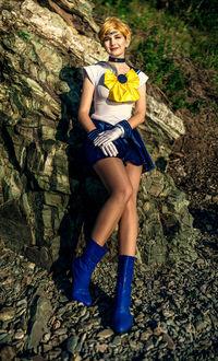 Portrait of young woman standing against rock