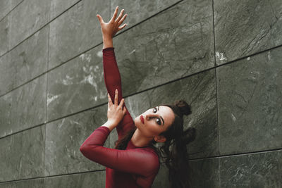 Portrait of woman sitting by wall outdoors