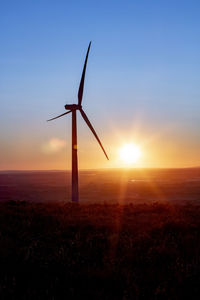 Wind turbines on field during sunset