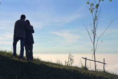 Couple standing on grass against sky