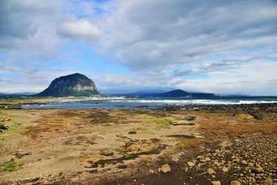 Scenic view of beach against cloudy sky