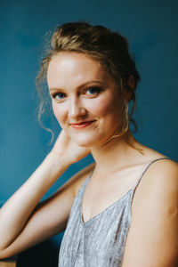 Portrait of smiling young woman against wall