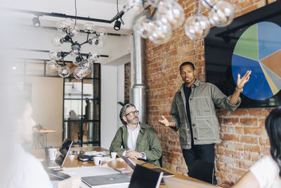 Businessman explaining pie chart to colleagues in meeting at office