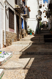 Footpath amidst buildings in city on sunny day