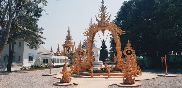 Statue amidst trees and buildings against sky