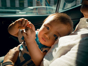 Portrait of cute baby relaxing with father in car