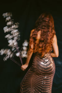 Rear view of woman standing against black background