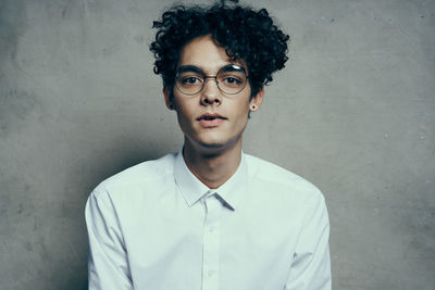 Portrait of young man standing against wall