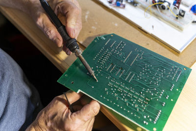 Senior man working on electronic circuits in his workshop, close up