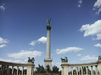 Statue in city against sky