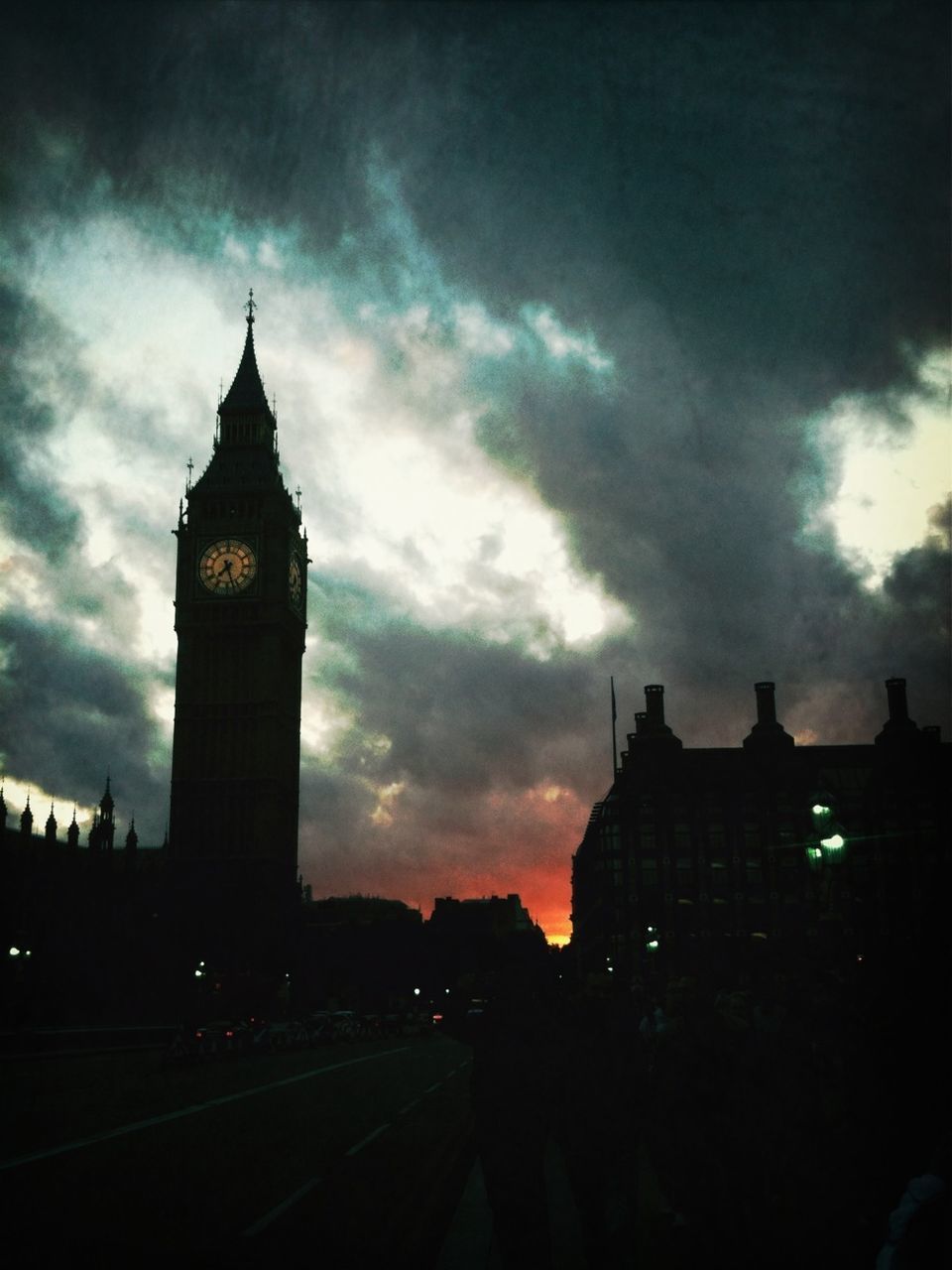 architecture, building exterior, built structure, sky, cloud - sky, city, cloudy, silhouette, dusk, clock tower, transportation, tower, road, street, weather, low angle view, sunset, car, cloud, travel destinations