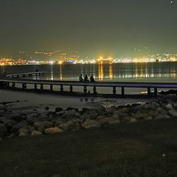 Scenic view of illuminated river against sky at night